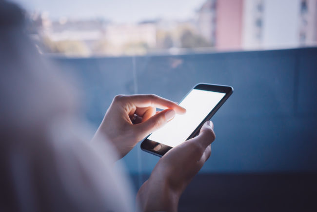 Girl touching a screen of her smarthone on the blurred background. Horizontal